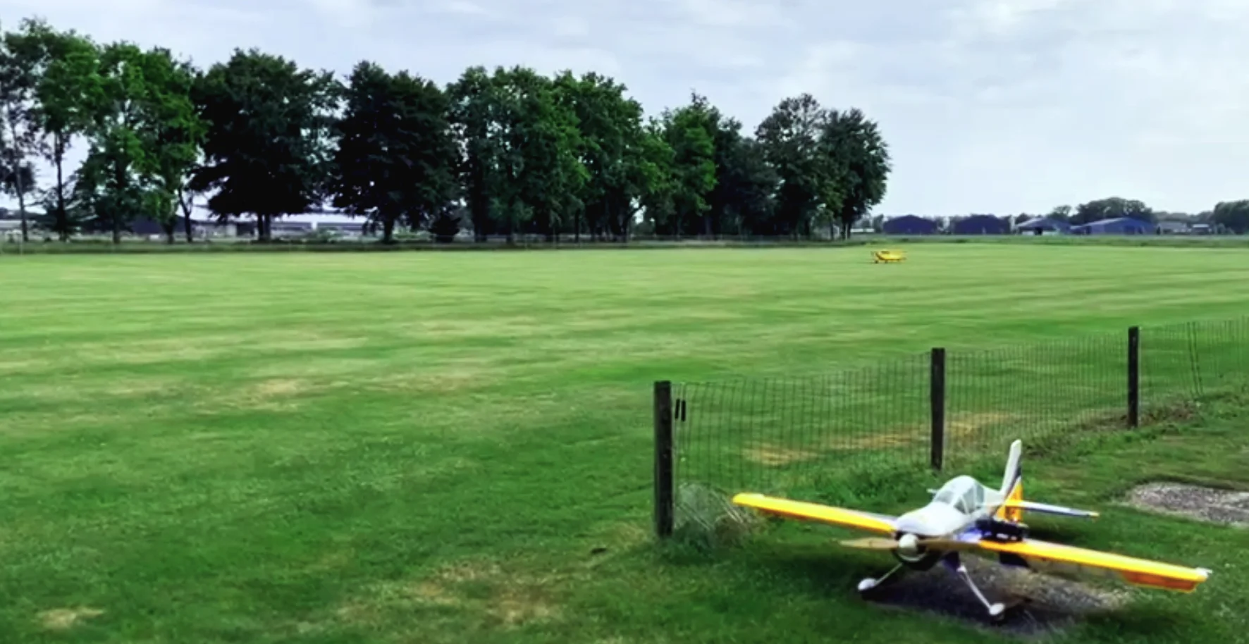 Het groene modelvliegveld van De Pioniers met een geel modelvliegtuig